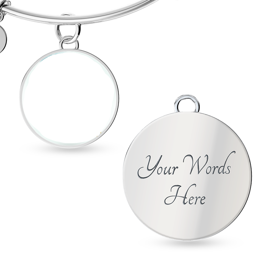 Silver bangle with round engraved charm on a white background